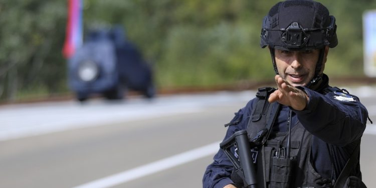 A Kosovo police officer guards a road near the village of Banjska, 55 kilometers (35 miles) north of the capital Pristina, northern Kosovo, Sunday, Sept. 24, 2023. Prime Minister Albin Kurti on Sunday said one police officer was killed and another wounded in an attack he blamed on support from neighboring Serbia, increasing tensions between the two former war foes at a delicate moment in their European Union-facilitated dialogue to normalize ties. (AP Photo/Bojan Slavkovic)